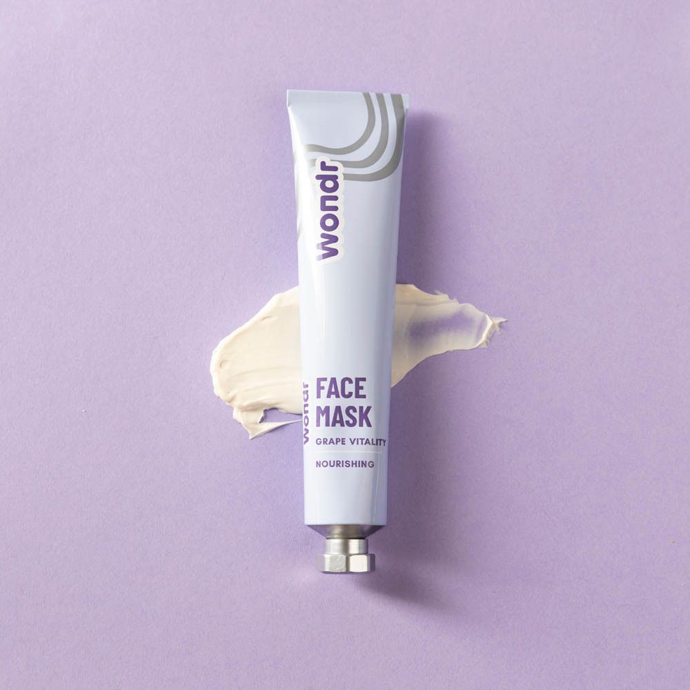 Tube et crème sur fond violet. Inscription : Wondr, Face Mask, Grape Vitality, Nourishing. Étale de crème.
