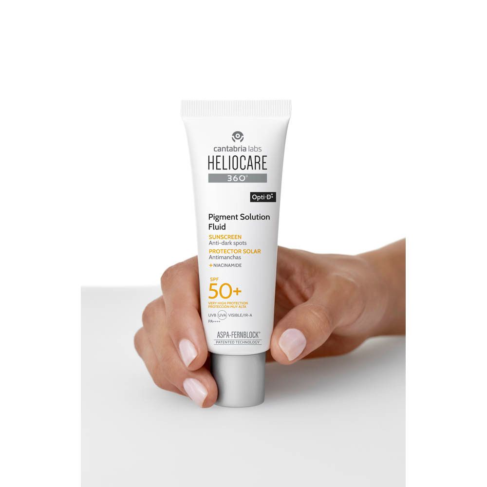 Main tenant un tube Heliocare 360 Fluide Solution Pigment SPF50+. Crème sur la main.