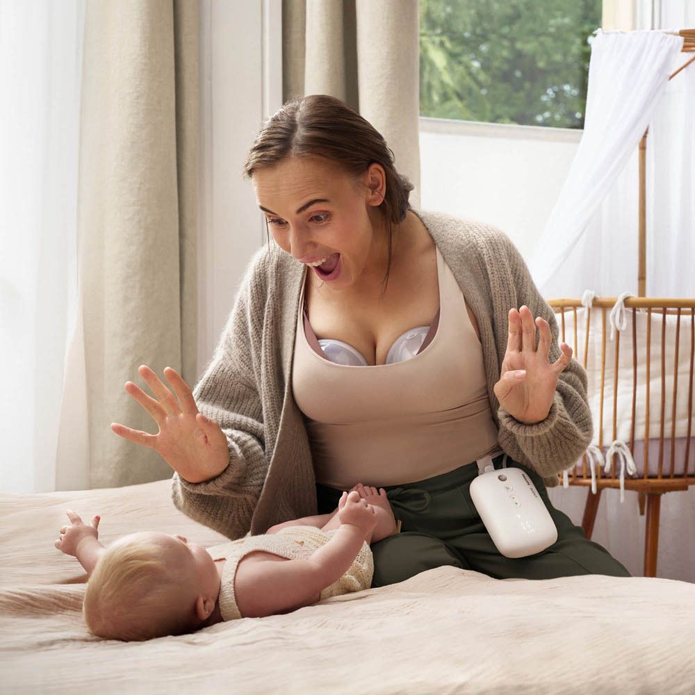 Femme avec tire-lait. Bébé sur le lit. Appareil blanc.