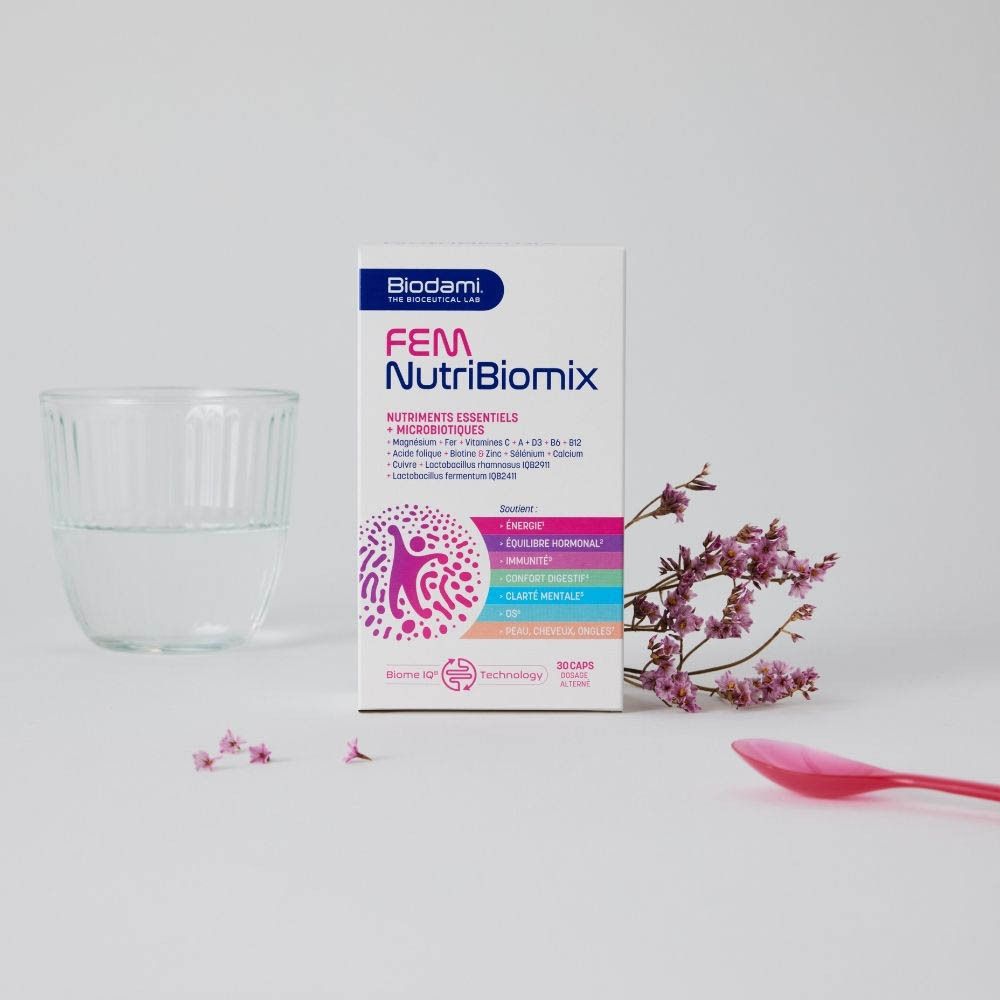 Boîte FEM NutriBiomix, verre d'eau, cuillère rose, fleurs. Sur fond blanc.