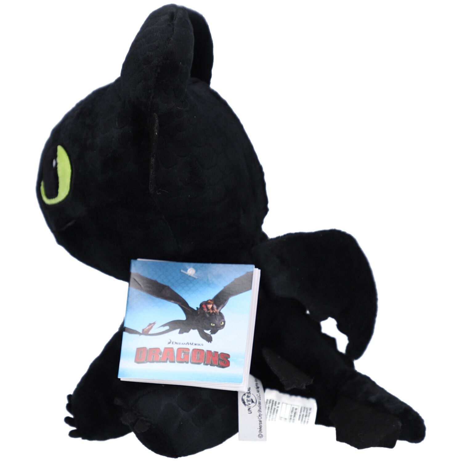 Peluche noire en forme de dragon avec des yeux jaunes et une étiquette. Vue de côté.