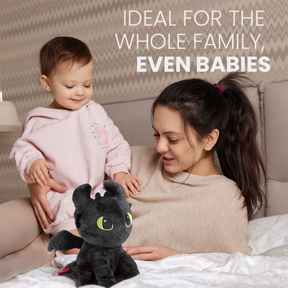 Dragon noir en peluche avec un bébé et une femme sur un lit.