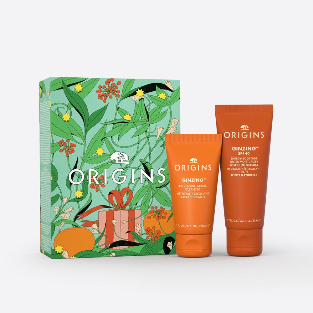 Coffret cadeau avec deux tubes oranges et une boîte à motifs floraux. Les tubes portent les inscriptions "GINZING" et "ORIGINS".