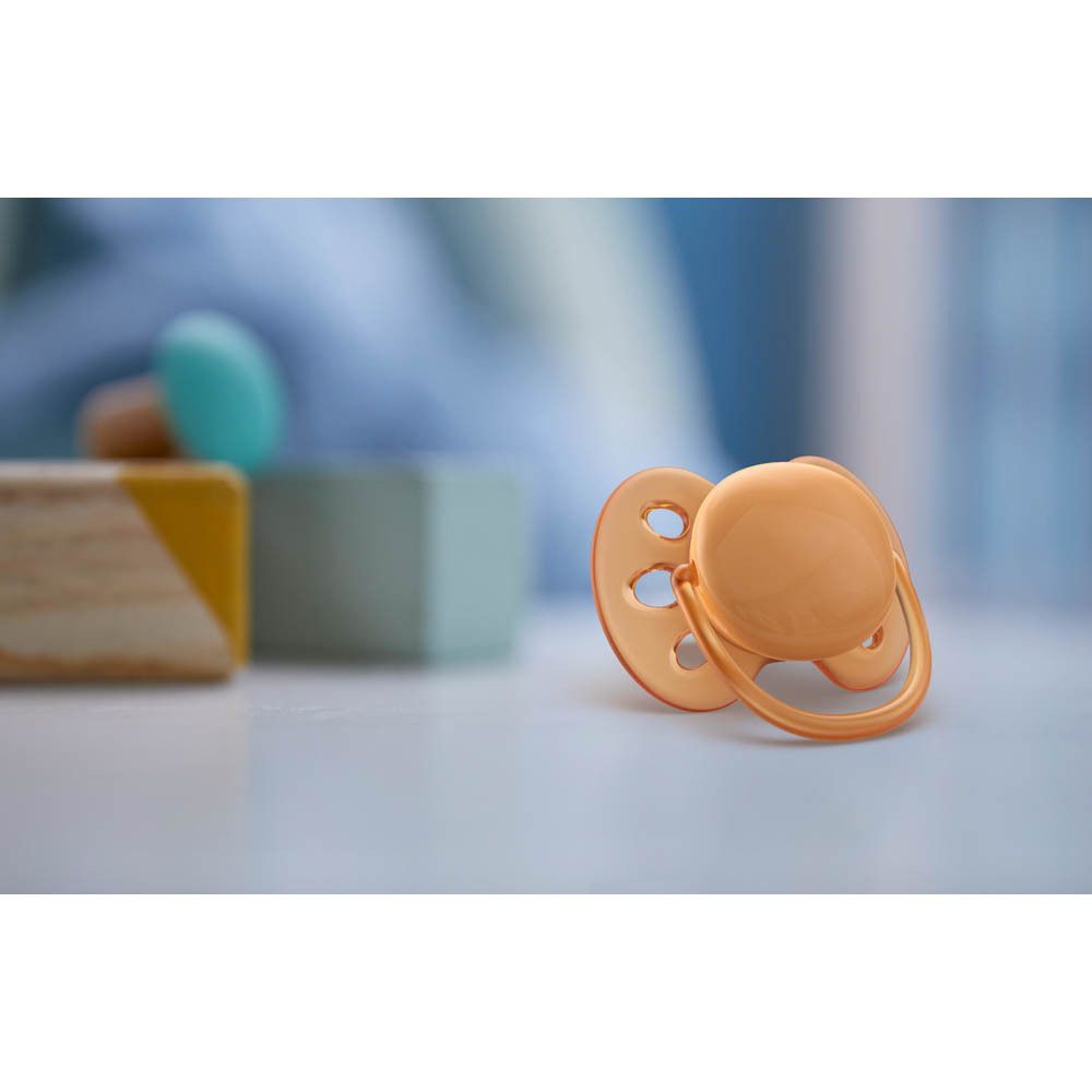 Deux sucettes Philips Avent, bleu clair et vert, dans une boîte de rangement transparente.