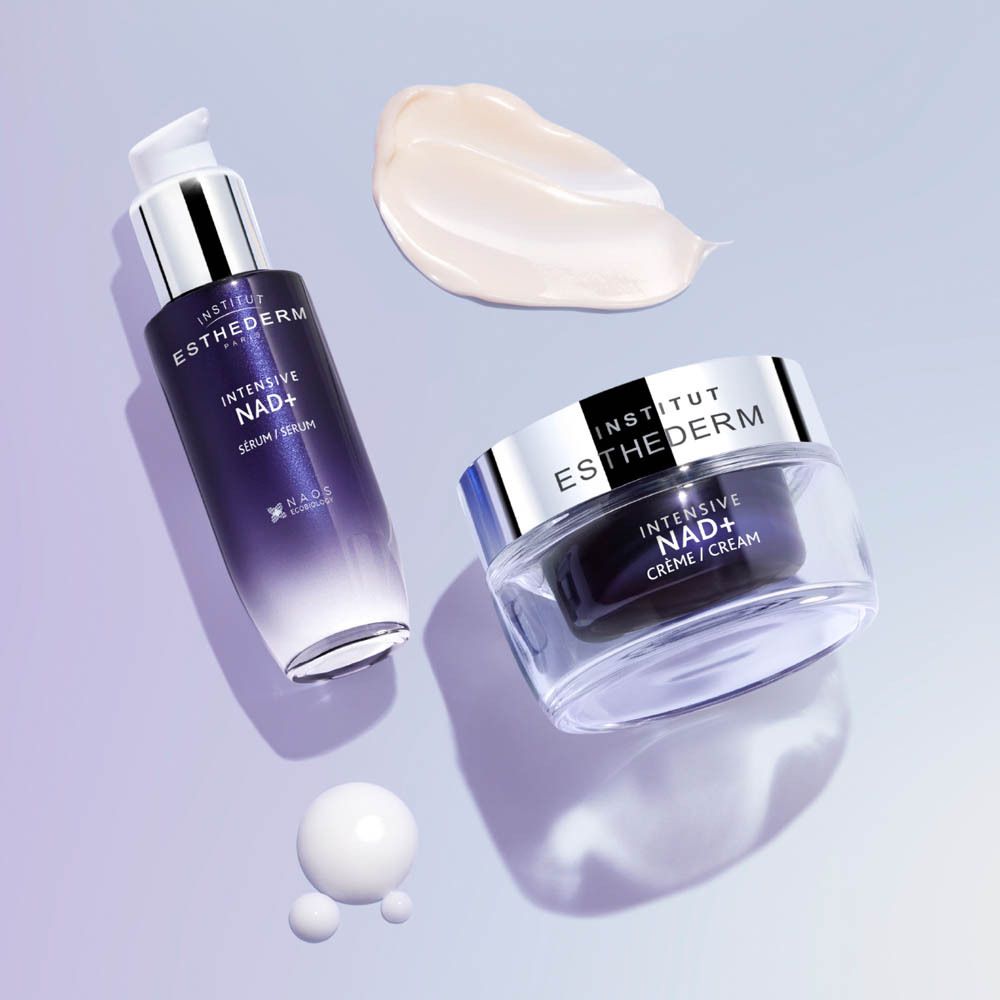 Pot Institut Esthederm avec couvercle argenté, base en verre transparente et contenu foncé.