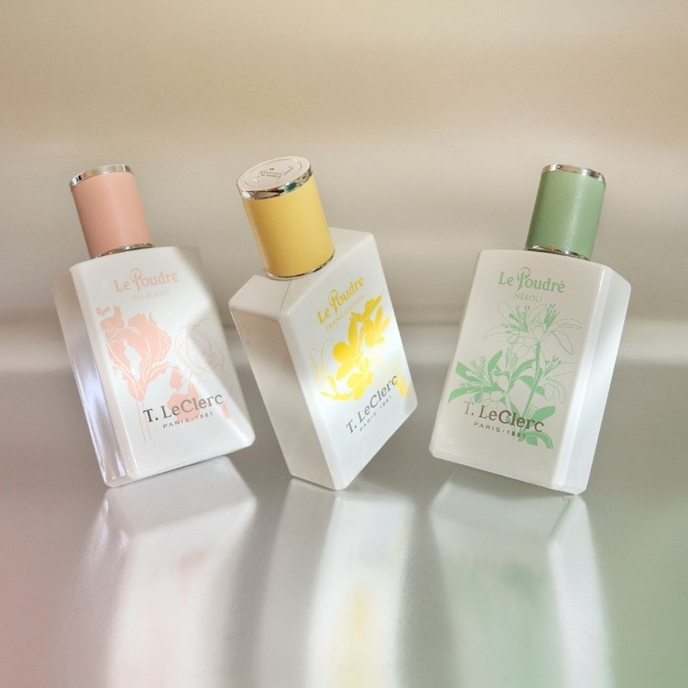 Flacon T. LeClerc Eau de Parfum Le Poudré Frangipanier au milieu de fleurs.