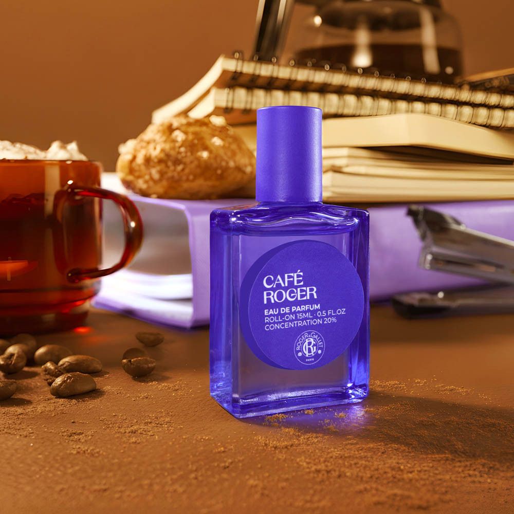 Parfum roll-on sur une table avec du café, des cahiers et des trombones.