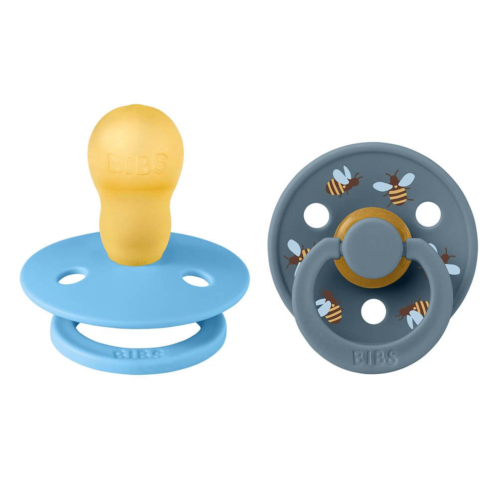 Deux sucettes. Une bleue avec tétine jaune, une bleu foncé avec motifs abeilles. Marque BIBS.