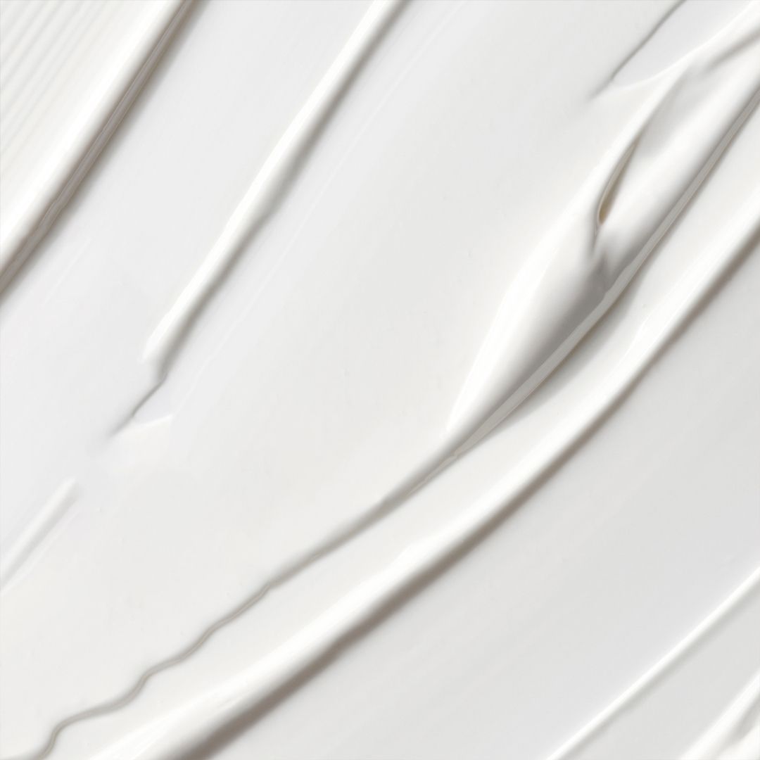 Gros plan de crème blanche. La crème est appliquée en lignes ondulées.