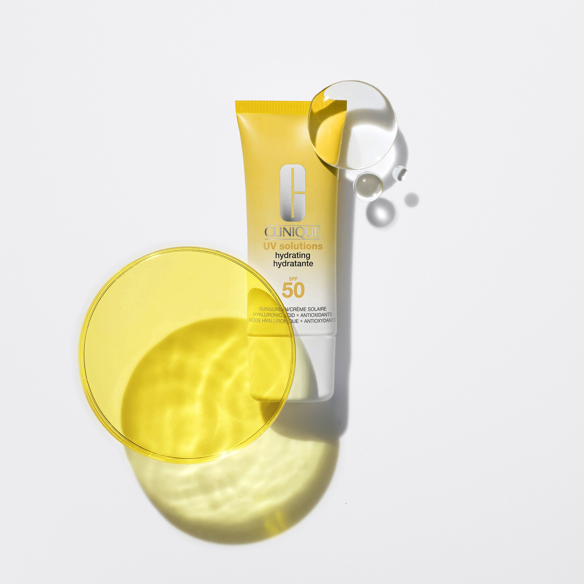 Tube jaune et bouchon blanc. Inscription: Clinique UV solutions hydrating hydratante SPF 50. Crème solaire.