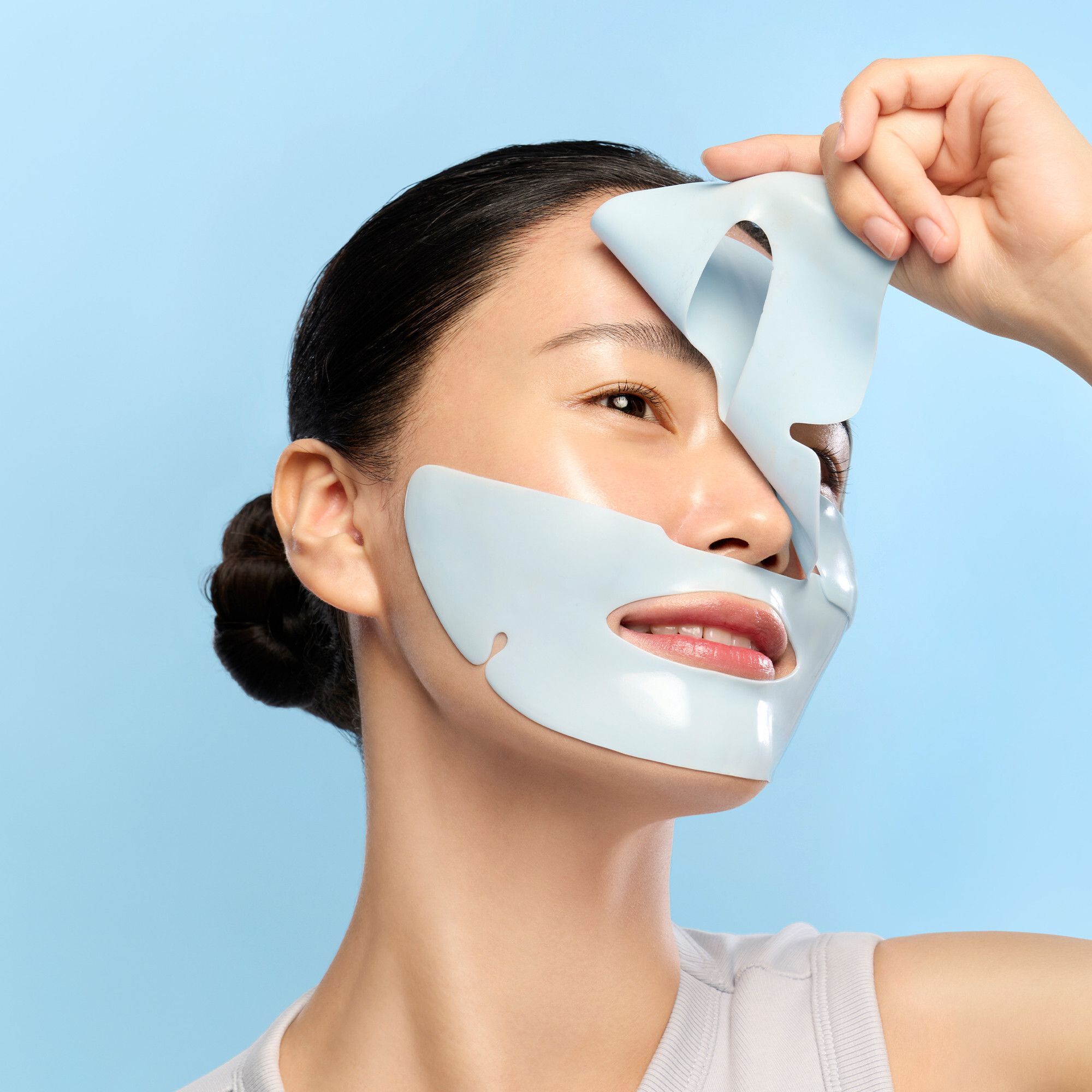 Personne tenant un masque facial bleu. Masque avec ouvertures pour les yeux et la bouche. Sur fond bleu.