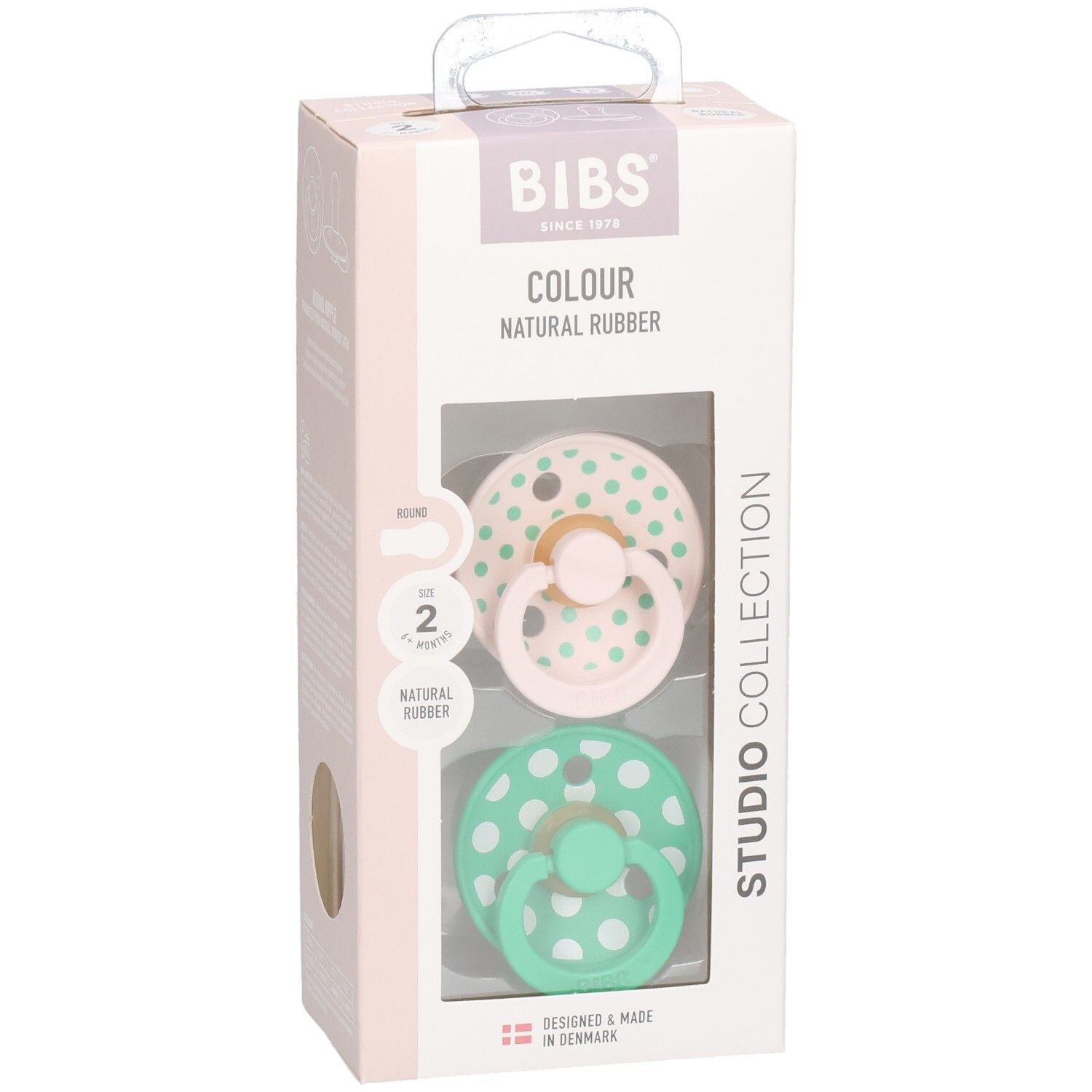 Boîte de deux sucettes. Sucettes roses et vertes à pois blancs. Marque : BIBS. Caoutchouc naturel.