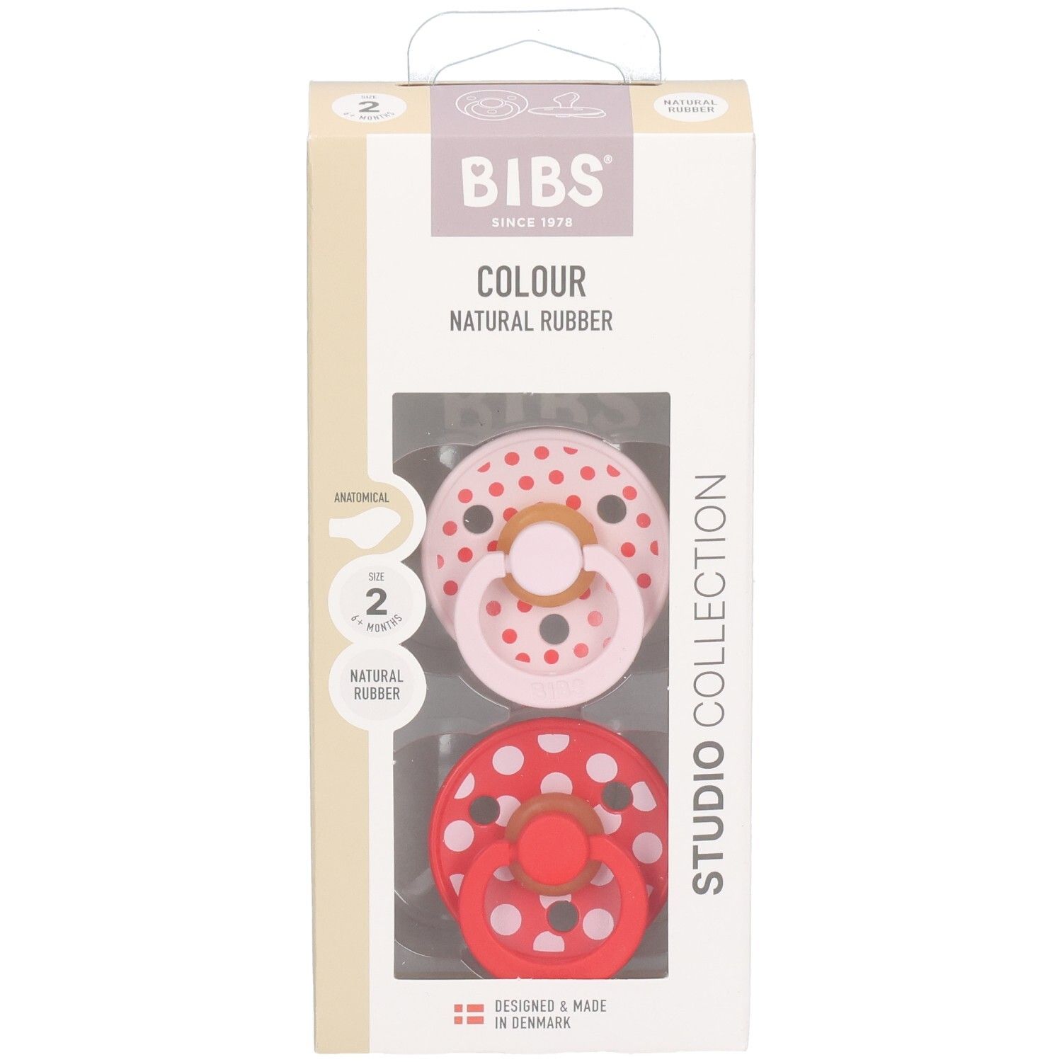 Boîte contenant deux sucettes. Sucettes rose et rouge à pois blancs. Logo BIBS et informations sur le produit.