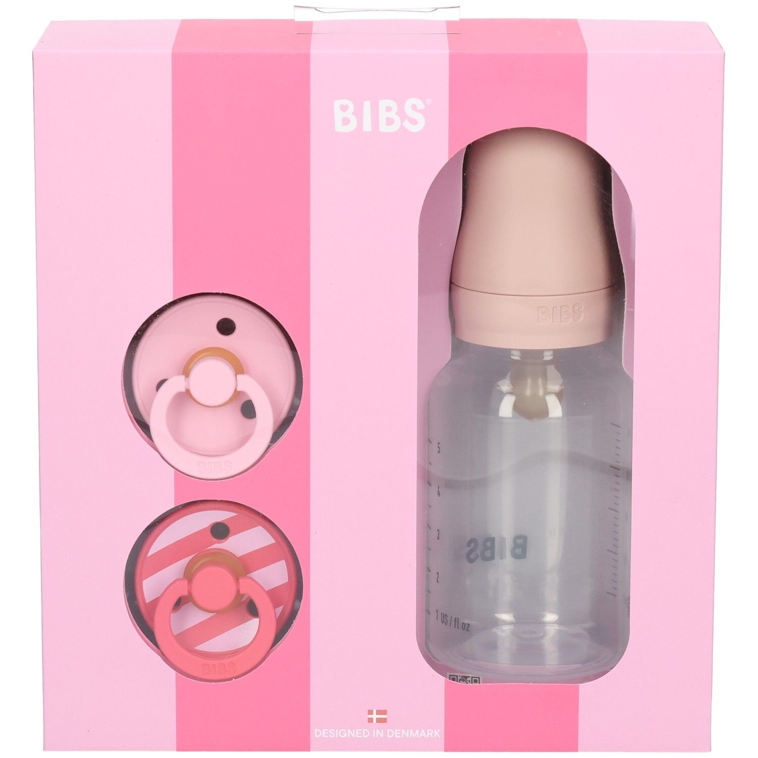 Coffret rose avec sucettes et biberon. Logo BIBS. Biberon transparent avec graduation. Deux sucettes.