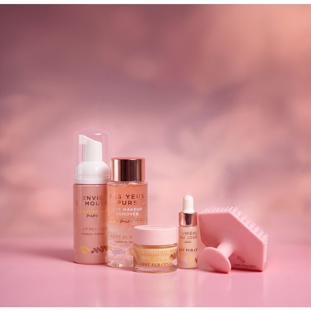 Coffret Cent Pur Cent Travel Essentials avec quatre soins et un applicateur brosse nettoyante dans une boîte rose.