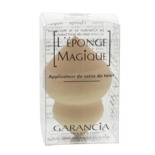 Éponge beige dans un emballage plastique transparent. Inscription : ÉPONGE MAGIQUE, GARANCIA PARIS. Applicateur de soins de teint.