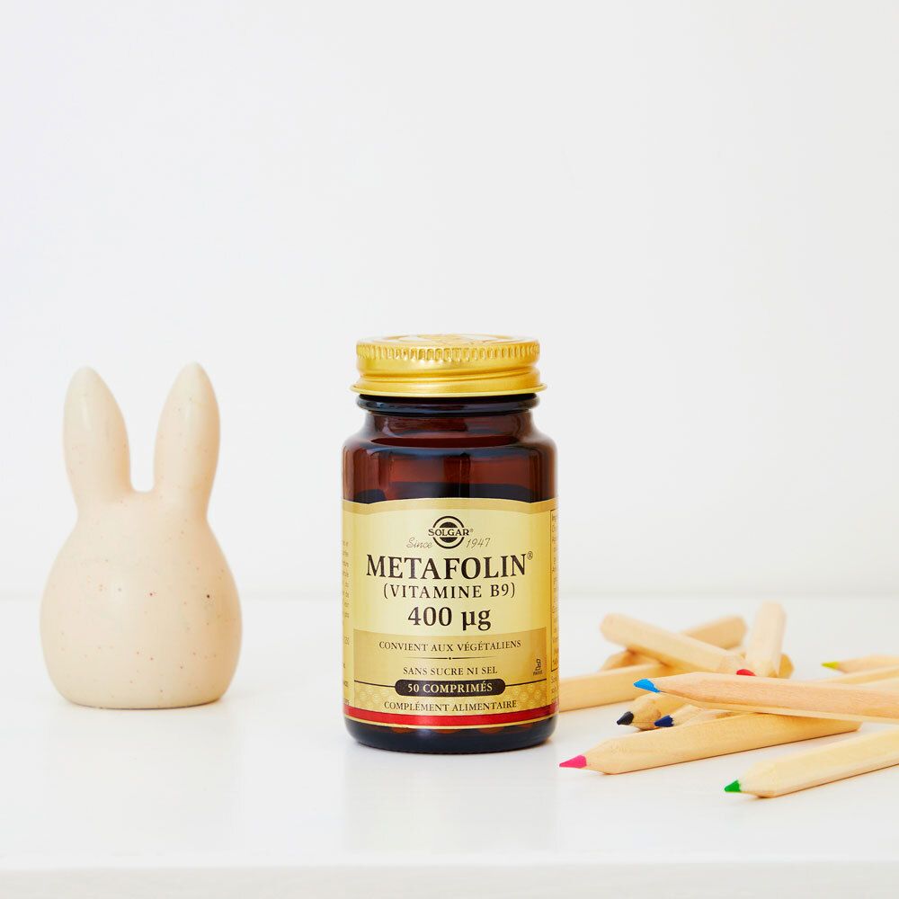 Flacon brun, bouchon doré, à côté de jouets. Étiquette SOLGAR, METAFOLIN (Vitamine B9).