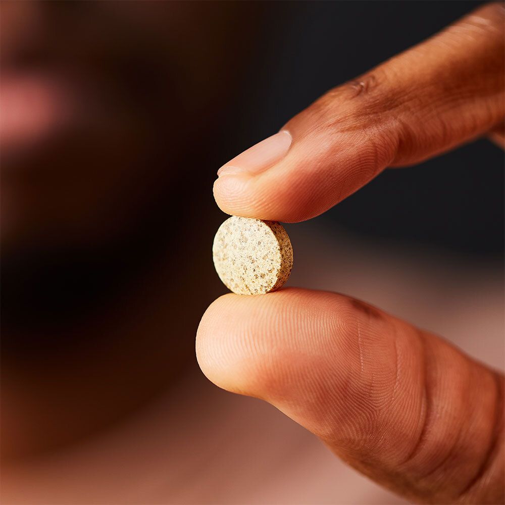 Main tenant un comprimé. Comprimé entre le pouce et l'index.