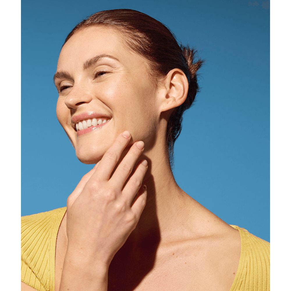 Femme souriante touchant son visage, eau micellaire NIVEA Rose Care pour une peau pure.