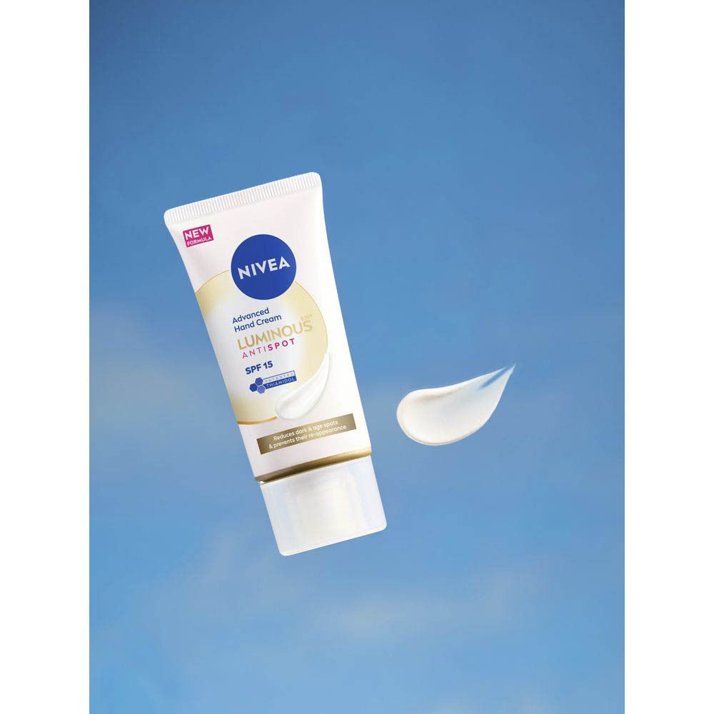 Une main tient un tube de crème mains NIVEA® CELLULAR LUMINOUS630® devant un ciel bleu.