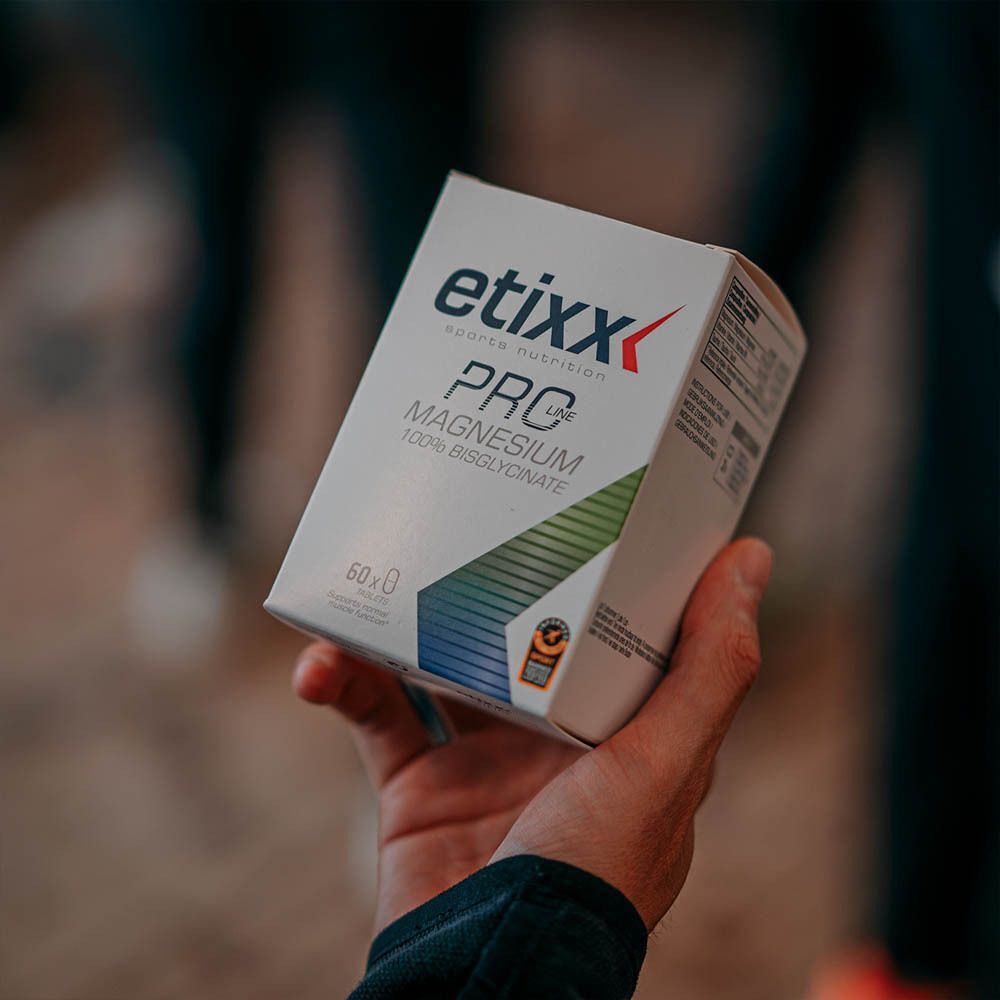 Une boîte blanche tenue par une main. Inscription: etixx PRO Magnesium 100% Bisglycinate. 60 gélules. Avec label de qualité.