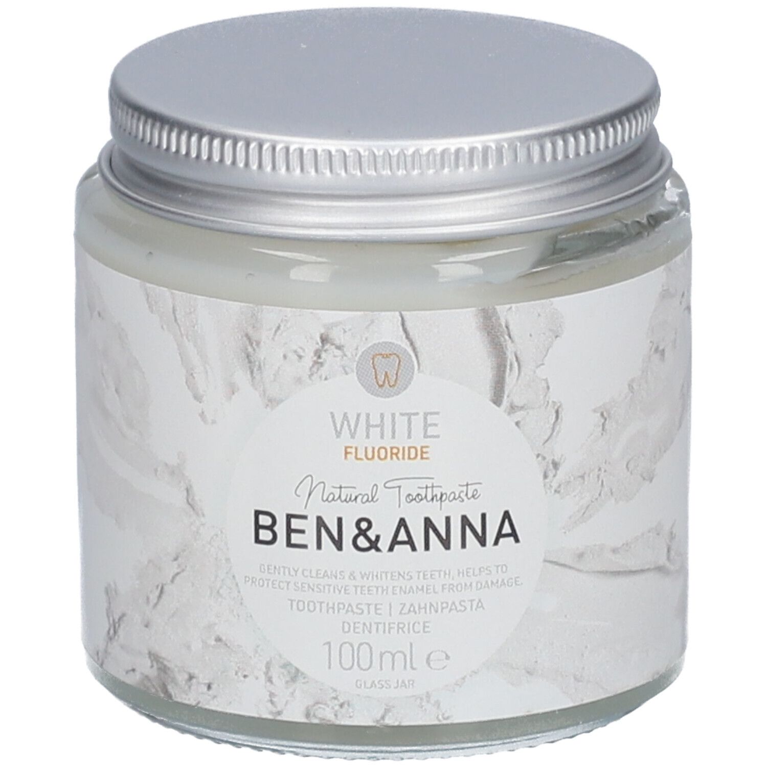 Pot de dentifrice en verre avec couvercle argenté. Étiquette blanche avec nom du produit et indication fluor. Marque : Ben & Anna.