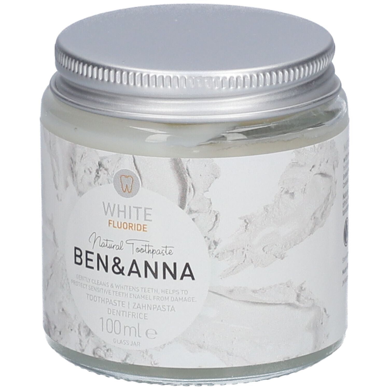 Pot de dentifrice en verre avec couvercle argenté. Étiquette blanche avec nom du produit et indication fluor. Marque : Ben & Anna.