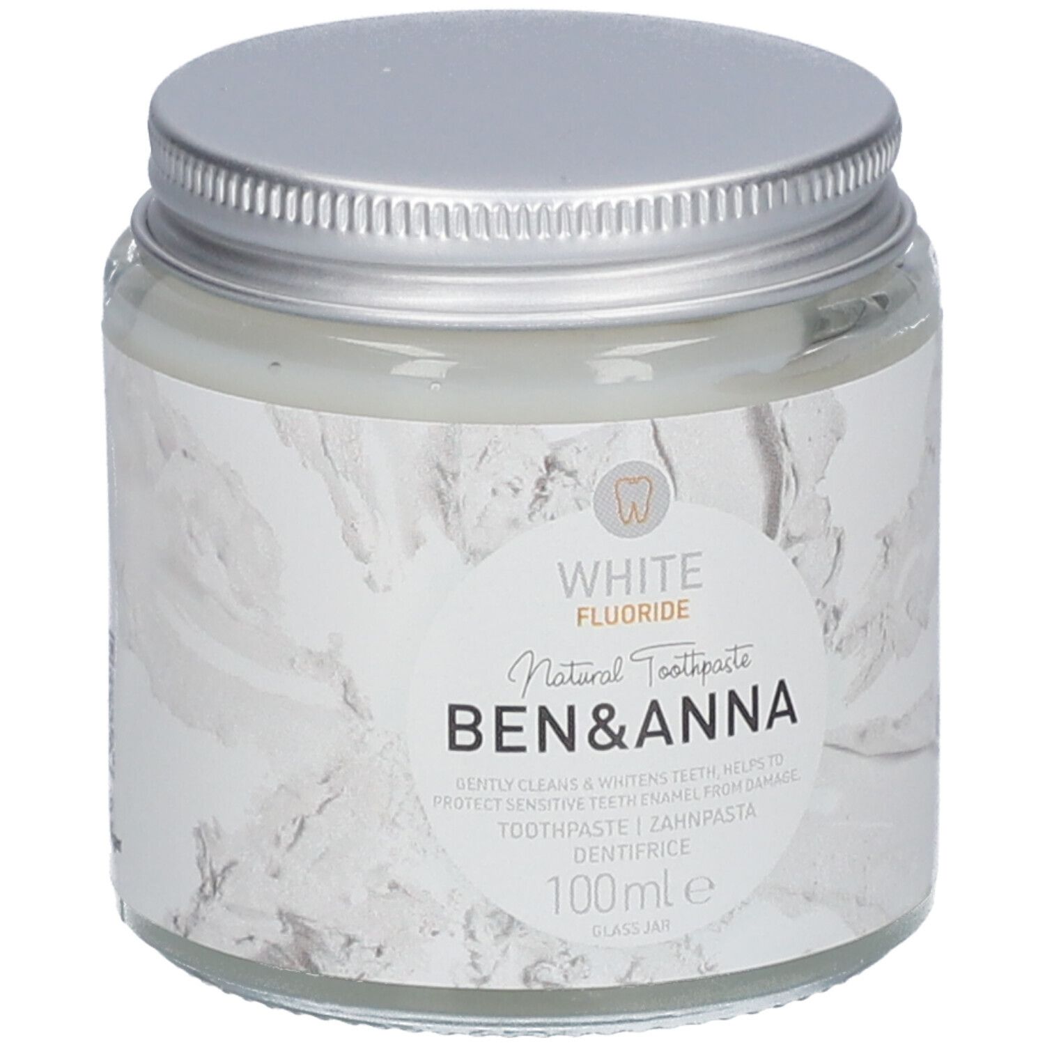 Pot de dentifrice en verre avec couvercle argenté. Étiquette blanche avec nom du produit et indication fluor. Marque : Ben & Anna.