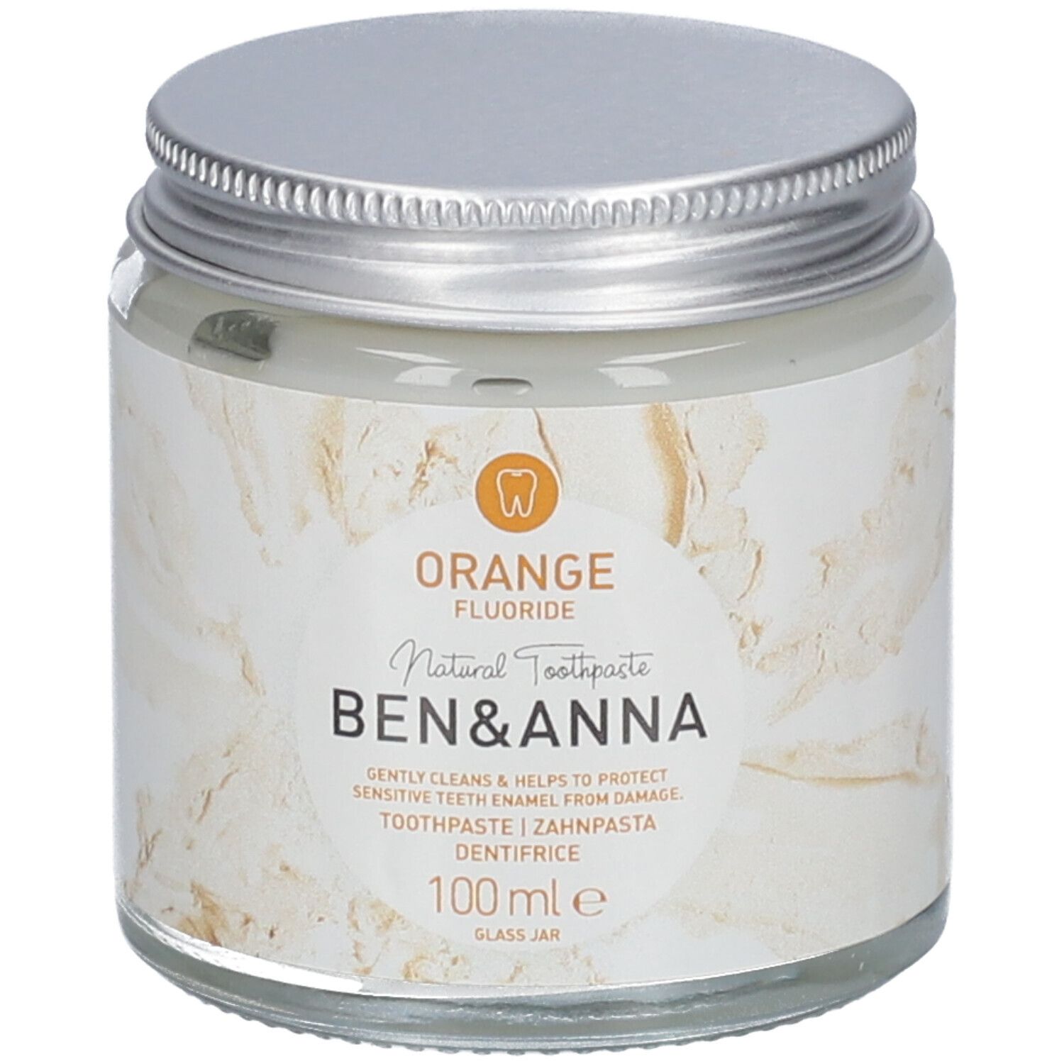 Dentifrice en pot de verre, couvercle argenté. Étiquette avec texte Orange, Fluoride, Ben & Anna, dentifrice, 100 ml.