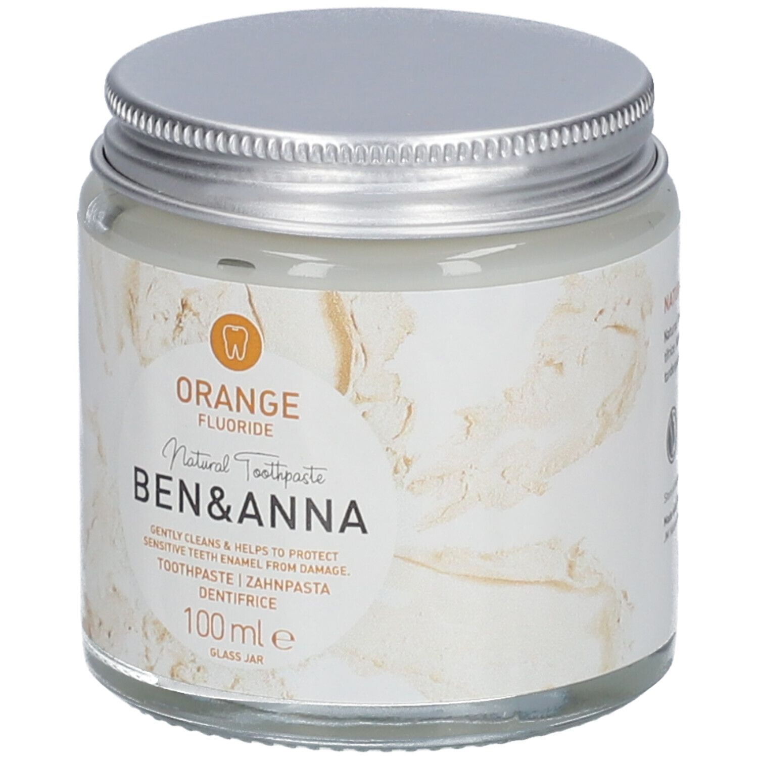 Dentifrice en pot de verre, couvercle argenté. Étiquette avec texte Orange, Fluoride, Ben & Anna, dentifrice, 100 ml.
