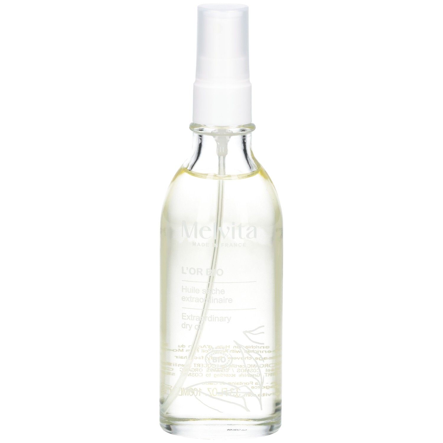 Flacon en verre transparent avec vaporisateur. Contient de l'huile dorée. Étiquette avec texte.