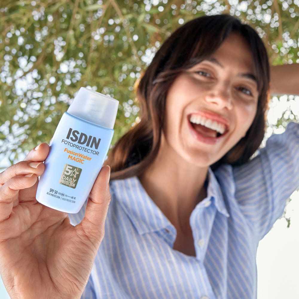 Femme tenant un flacon de crème solaire ISDIN Fusion Water Magic. SPF 50+.