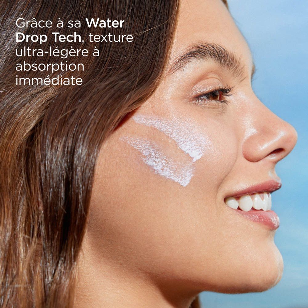 Femme avec de la crème solaire sur la joue, montrant la texture légère et l'absorption immédiate.
