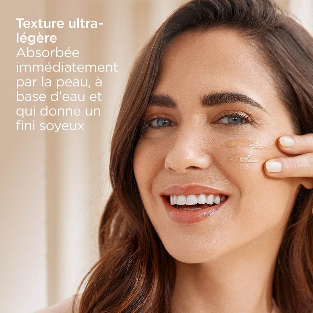 Femme avec maquillage bleu pour les yeux appliquant une texture légère à base d'eau sur sa joue.