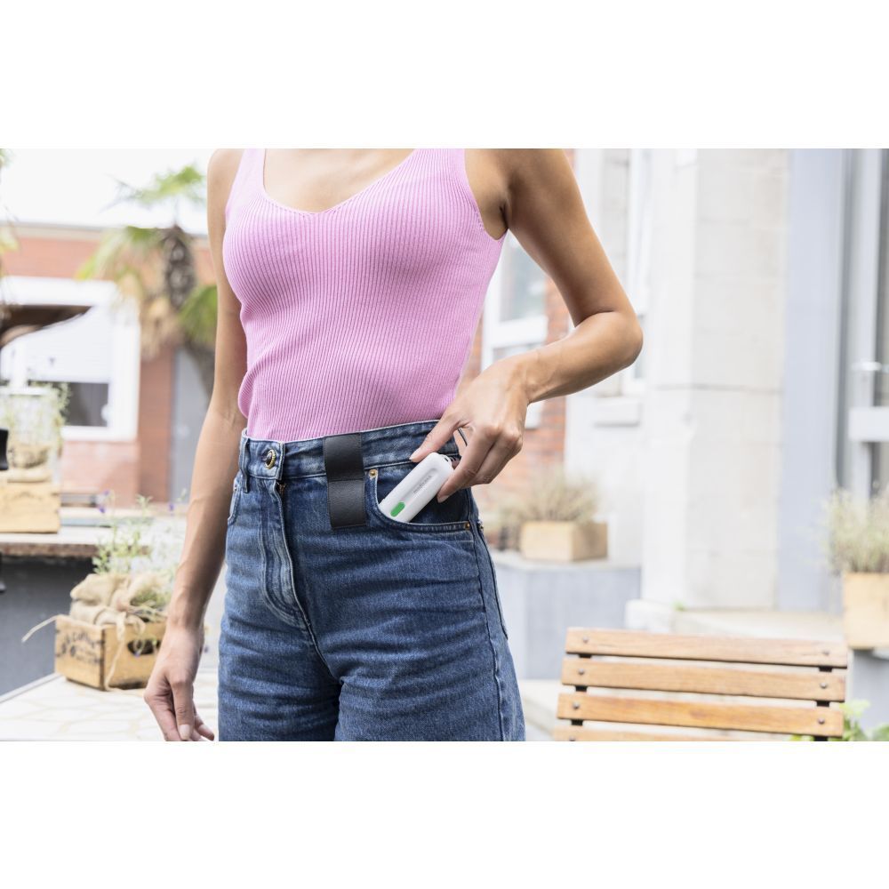 Femme met un appareil blanc dans sa poche. Short en jean.