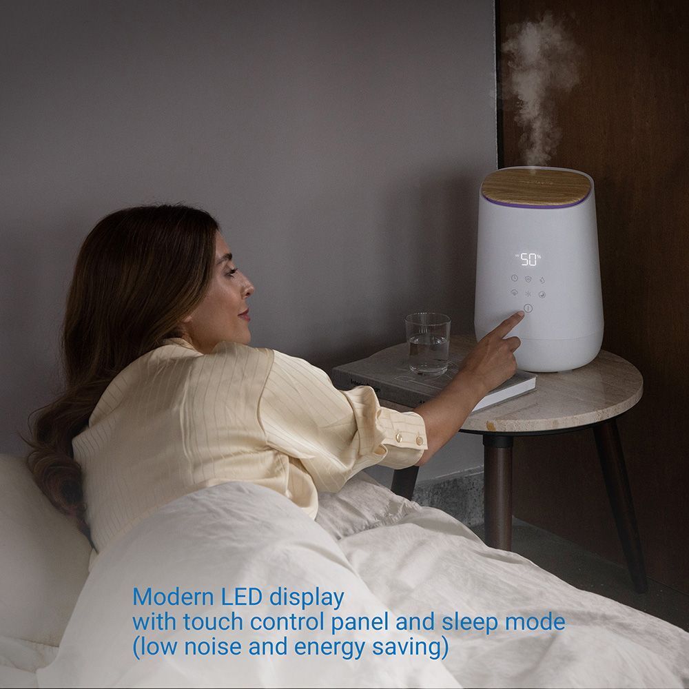 Humidificateur blanc avec couvercle en bois. Femme utilise l'appareil. Affichage numérique.