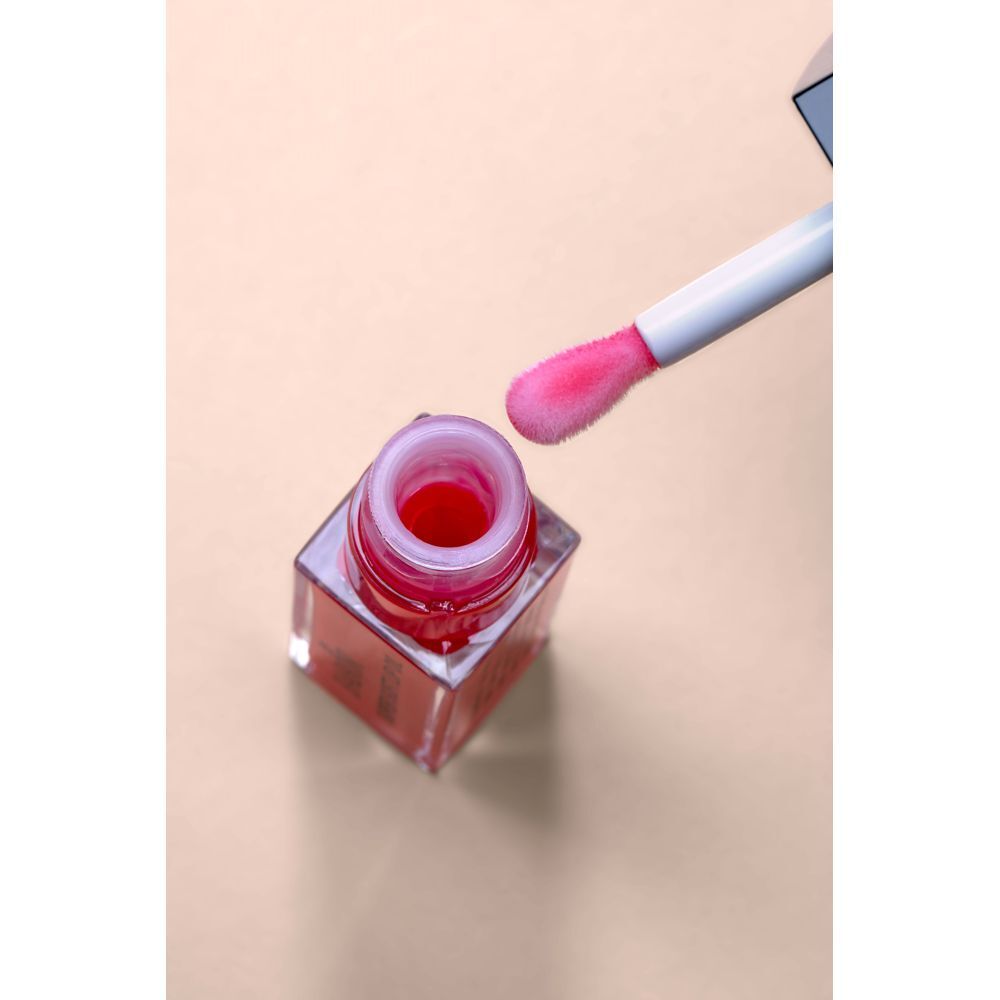 Flacon d'huile à lèvres ouvert avec applicateur. Huile rose dans le flacon. Applicateur à pointe rose.