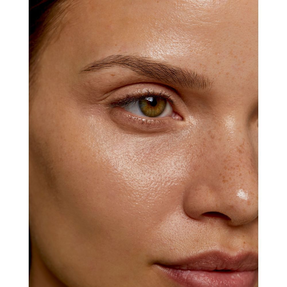 Gros plan d'un visage avec des sourcils. Peau avec des taches de rousseur et des yeux verts.