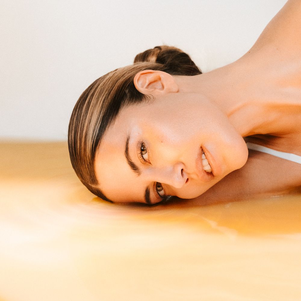 Femme allongée dans un liquide jaune.