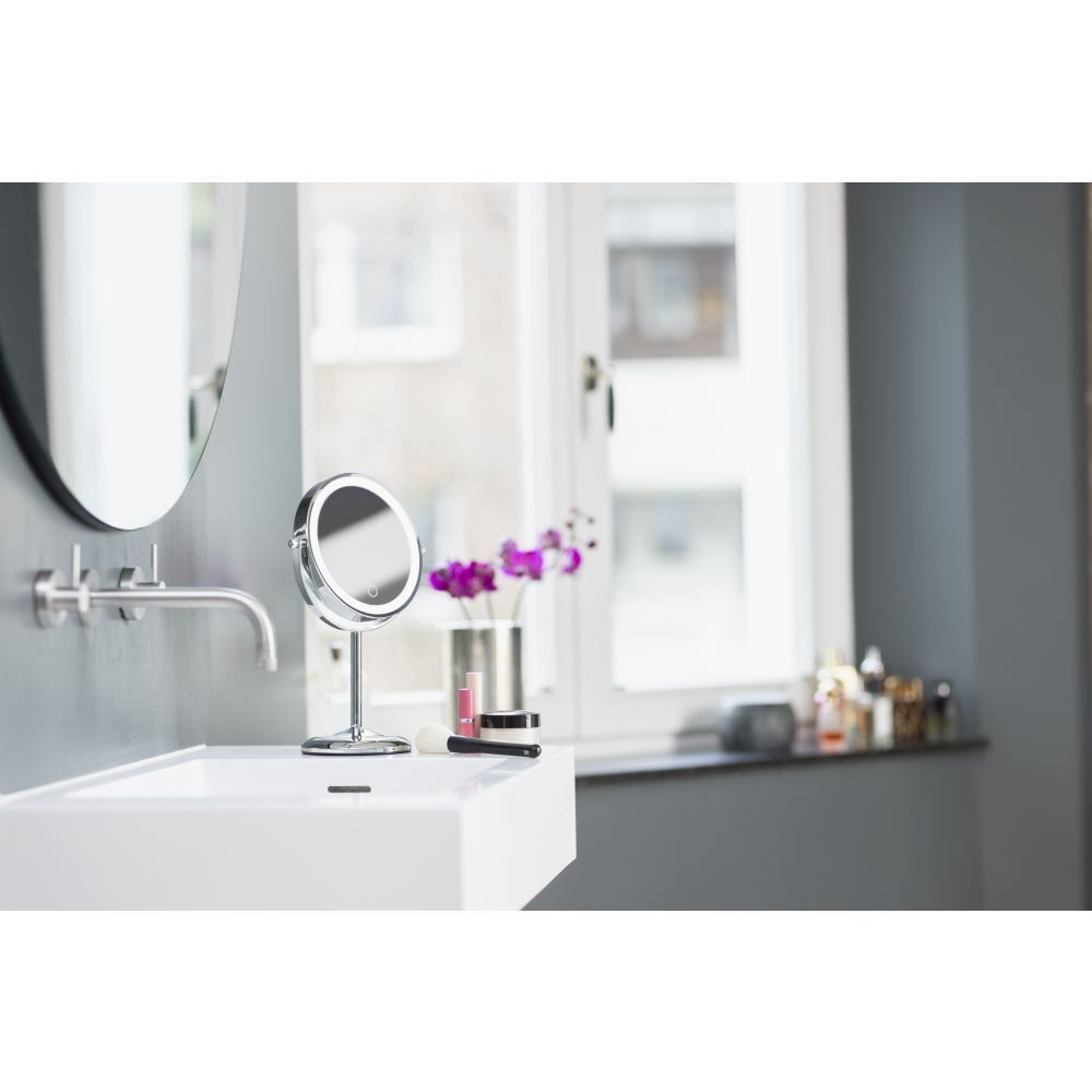 Miroir cosmétique dans un environnement de salle de bain. Sur un lavabo. Miroir, robinet, fenêtre en arrière-plan.