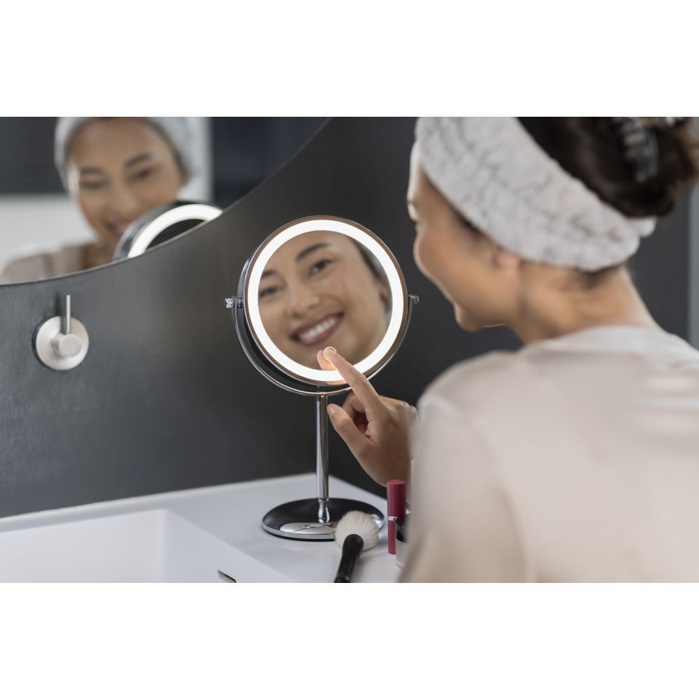 Femme utilisant un miroir cosmétique. Miroir avec éclairage LED. La femme touche le miroir.