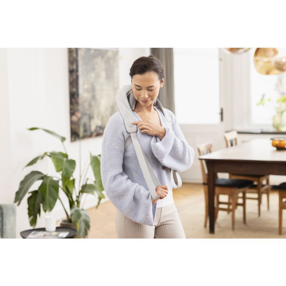 Femme avec masseur de cou. Masseur gris. Sangles sur les épaules.