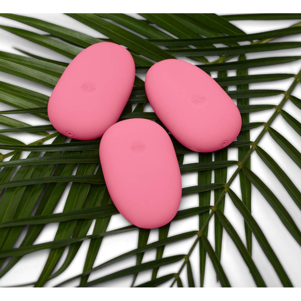 Trois vibrateurs roses en forme d'œuf sur des feuilles. Logo: ILS. Surface lisse.