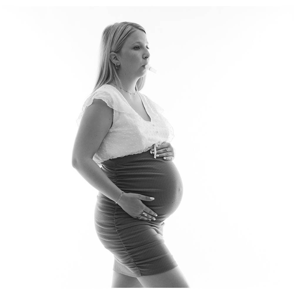 Femme enceinte avec embout dans la bouche. Vue de côté. Fond blanc.
