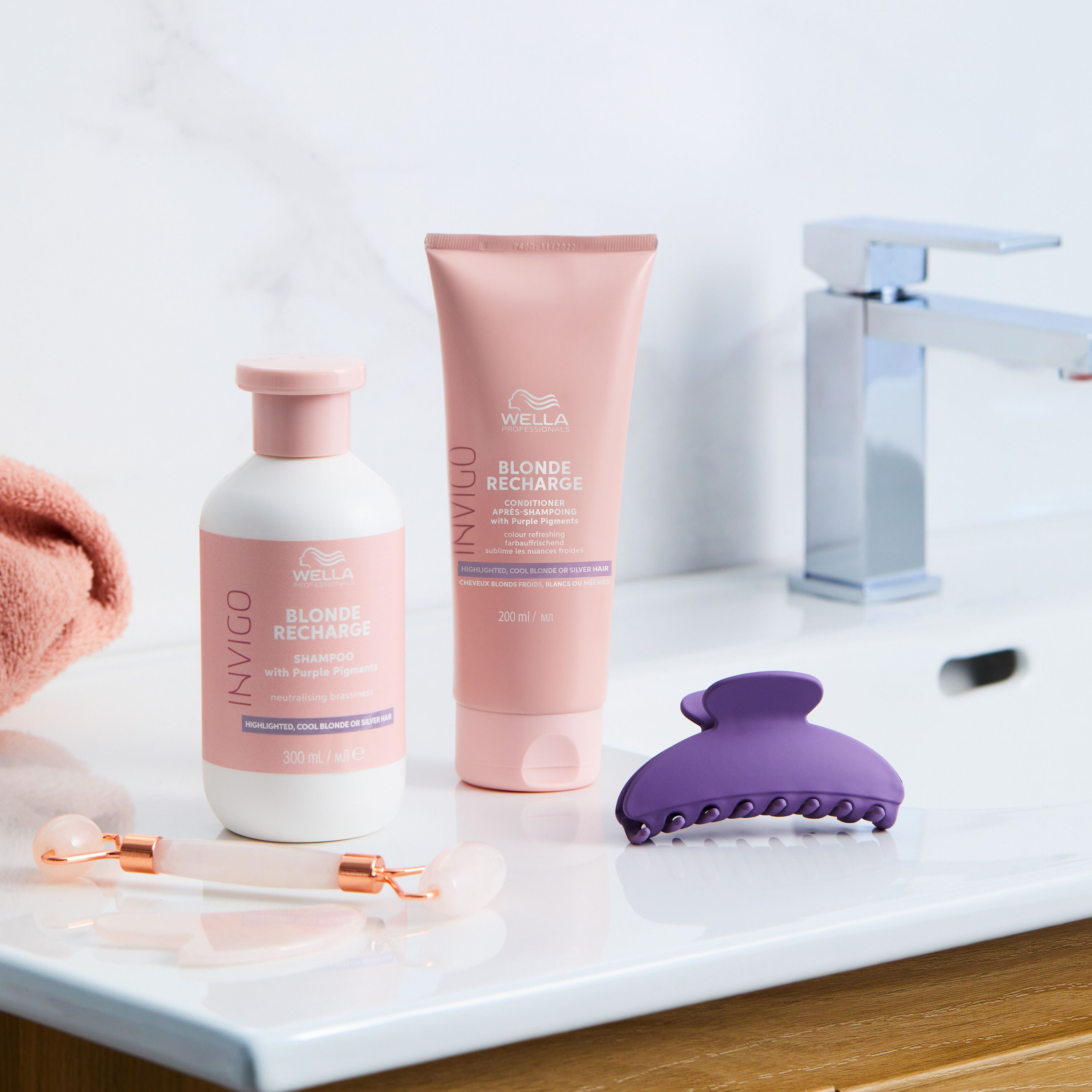Scène de salle de bain. Wella Invigo Blonde Recharge Conditioner, bouteille, pince à cheveux, rouleau facial.