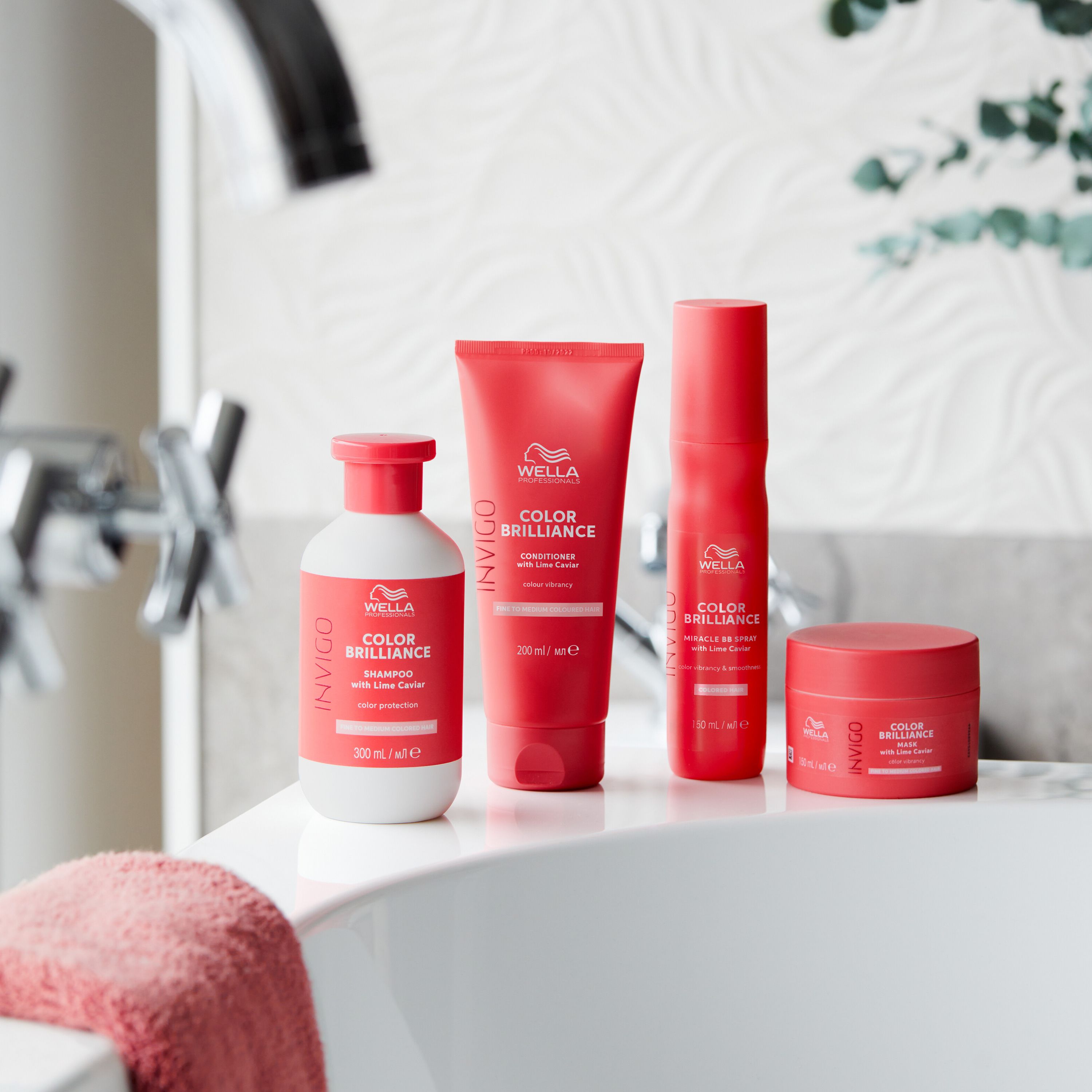Gamme de produits sur une baignoire. Wella Invigo Color Brilliance. Shampooing, après-shampooing, masque et spray. Emballage rouge.