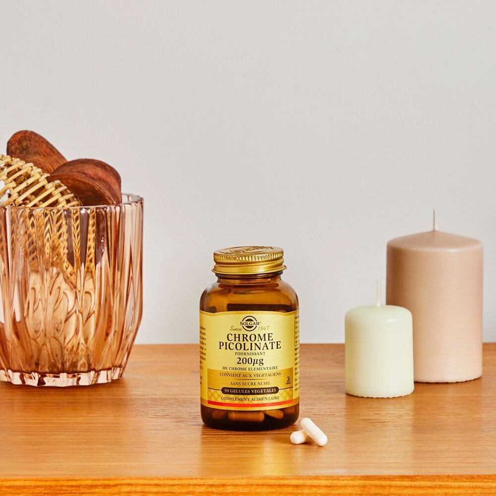 Un flacon de Chrome Picolinate Solgar sur une table avec des bougies et des décorations. Flacon en verre brun avec couvercle doré.