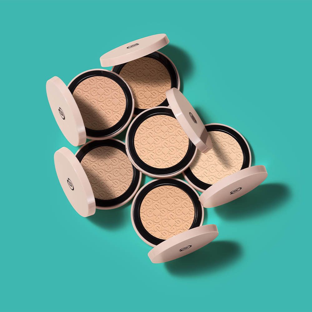 Plusieurs poudres compactes avec couvercle rose. Poudre beige. Logo sur la poudre.