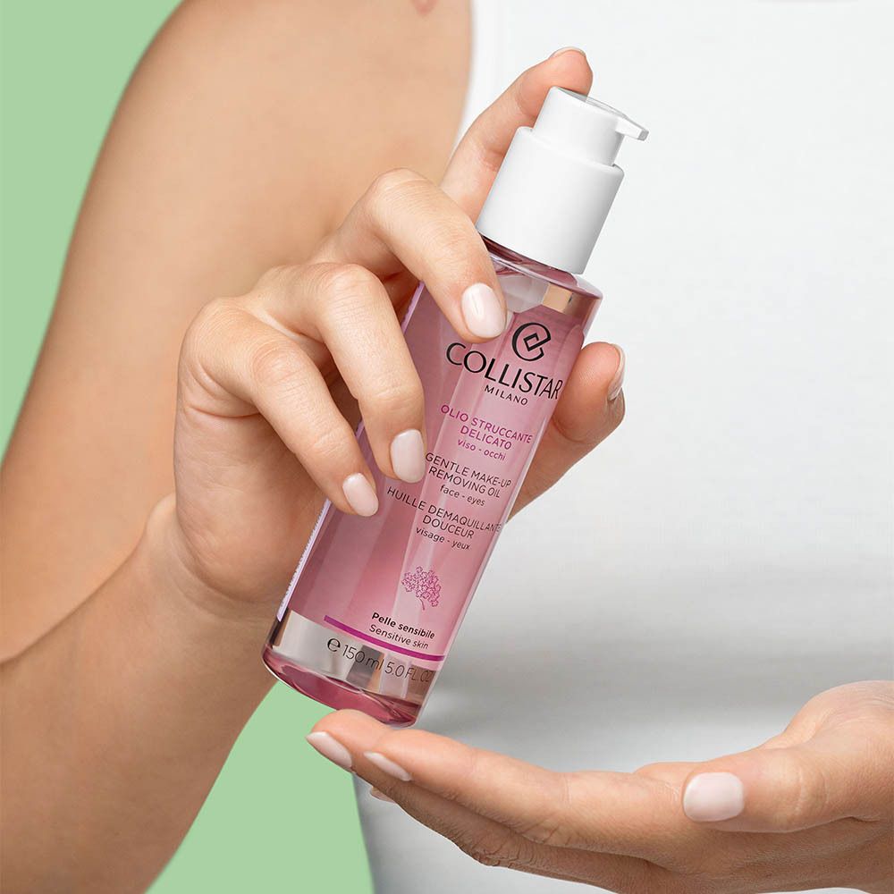 Une femme tient un flacon. Liquide rose dans un flacon transparent avec pompe blanche.