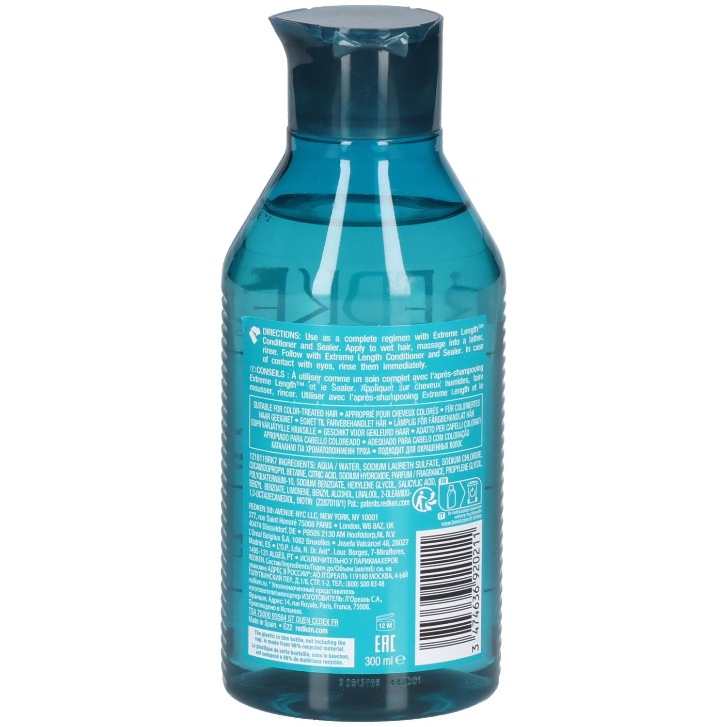 Dos d'un flacon de shampooing bleu transparent. Code-barres et texte. Contient des ingrédients et des instructions.